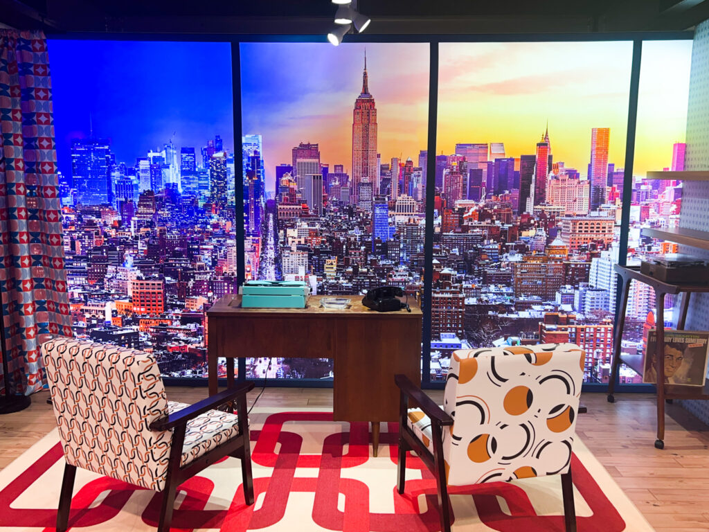 This image shows a large print of a New York City cityscape view set-up within a simulated office.