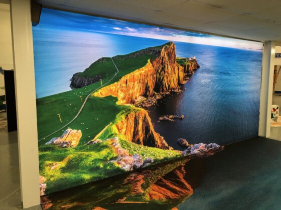 Large printed VorTex BLD300 soft signage fabric wall graphic of a coastal cliff installed in an interior space